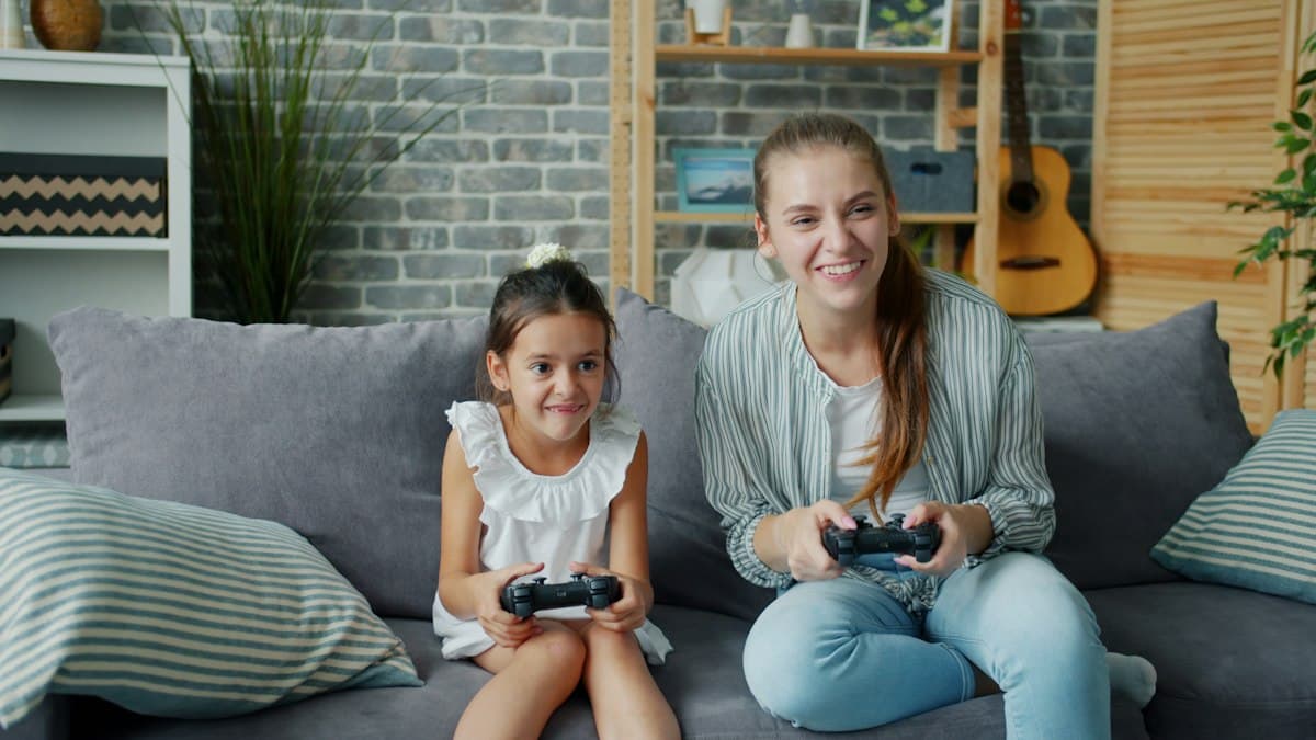 Madre e hija jugando juntas a videojuegos en el sofá